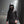 Person wearing a black raincoat with a hood on a foggy street at night.