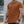 Man wearing a brown t-shirt with text, standing outdoors.