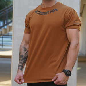 Man wearing a brown t-shirt with text, standing outdoors.