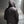 Person wearing a dark hooded jacket on a dimly lit sidewalk under a streetlight.