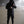 Person wearing a black hooded jacket and pants in a foggy outdoor setting