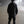 Person wearing a black jacket and pants standing on a foggy road at night.