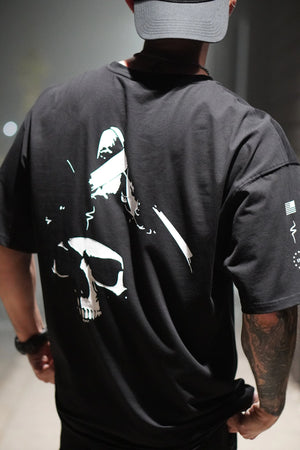 Person wearing a black t-shirt with a graphic design on the back, standing against a neutral background.