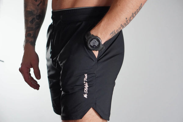 Person wearing black shorts with a No Straight Path® logo on a white background