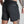 Person wearing black shorts with a pocket on a plain background