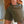 Person wearing green shorts and a brown shirt with a blurred background