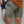 Person wearing green shorts with a white No Straight Path® logo, standing against a concrete wall.