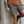 Person wearing a tan shirt and green shorts leaning against a concrete wall.