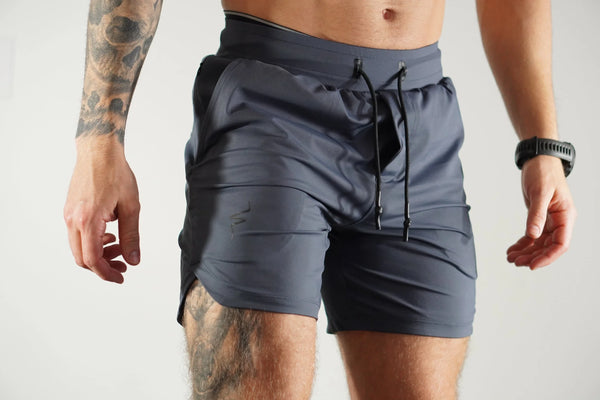 Person wearing gray-blue athletic shorts on a plain background