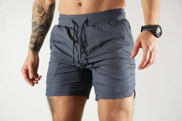 Person wearing gray-blue athletic shorts on a plain background