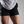 Female wearing black athletic shorts and a gray shirt on a plain background