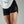Woman wearing black athletic shorts with a No Straight Path® logo on a gray background