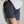 Person wearing dark blue shorts with a white shirt on a plain background