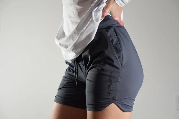 Woman wearing gray-blue athletic shorts with a plain background
