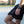 Person wearing black shorts with No Straight Path® text, sitting on a curb outdoors.