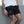 Person wearing black shorts with a No Straight Path® logo, standing against a gray wall.