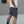 Person wearing light blue shorts with a tattooed arm against a plain background