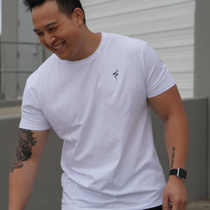 Man wearing a white t-shirt with a black No Straight Path® logo, standing outdoors.