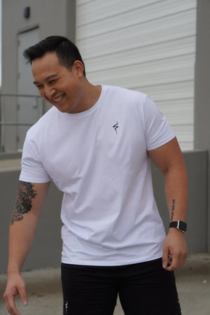 Man wearing a white t-shirt with a black No Straight Path® logo, standing outdoors.