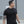 Man wearing a black t-shirt with a No Straight Path® logo, standing outdoors.
