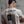 Person wearing a white t-shirt with a black flag design and a No Straight Path® text against concrete wall.