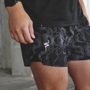 Person wearing black athletic shorts with white pattern and No Straight Path® logo.