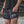Person wearing black athletic shorts with white text and patterns.