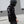 Person wearing a black helmet and black shirt with white graphics and text, standing in front of a gray warehouse.