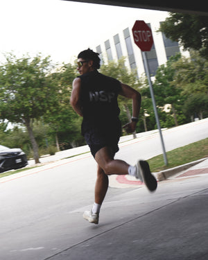 Person running on a sidewalk with a stop sign in the background