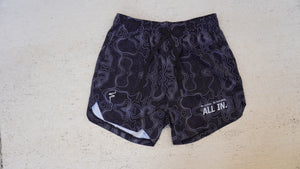 Black patterned shorts with white accents on a concrete surface