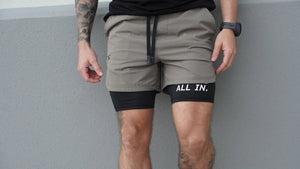Person wearing gray shorts with 'All In.' logo against a gray background