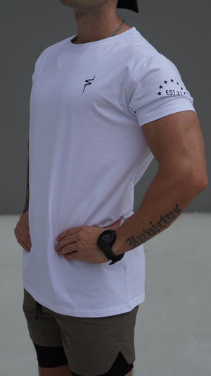 Person wearing a white t-shirt with star patterns on sleeves against a neutral background