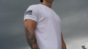 Person wearing a white t-shirt with a USA flag design on a cloudy day
