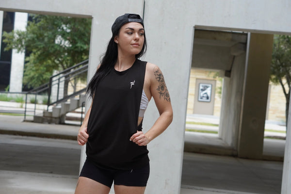 Woman in black athletic wear standing outdoors near a building