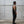 Man in black tank top and pants standing against a concrete wall.