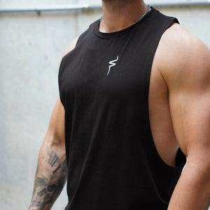 Person wearing a black tank top with a No Straight Path® logo, standing against a light-colored wall.