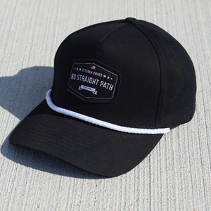 Black cap with white rope and a 'No Straight Path' patch on a textured surface