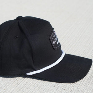 Black cap with a white rope on a light gray surface