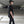 Person wearing a black outfit with white sneakers in an underground parking lot.