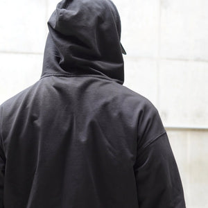 Person wearing a black hoodie with a plain background