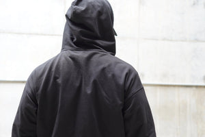 Person wearing a black hoodie with a plain background