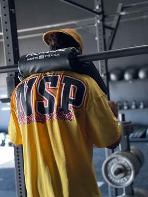 Person wearing a yellow 'NSP' shirt in a gym setting