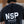 A person viewed from behind wearing a dark washed black t-shirt with a large white 'NSP' logo and 'NOSTRAIGHT PATH BUILT UNDER PRESSURE EST 2021' printed on the back, set against a rustic wooden background.